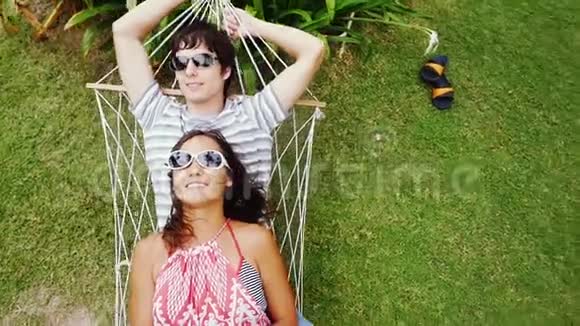 年轻的幸福夫妇戴着太阳镜在吊床上放松最高的视野慢动作1920x1080视频的预览图
