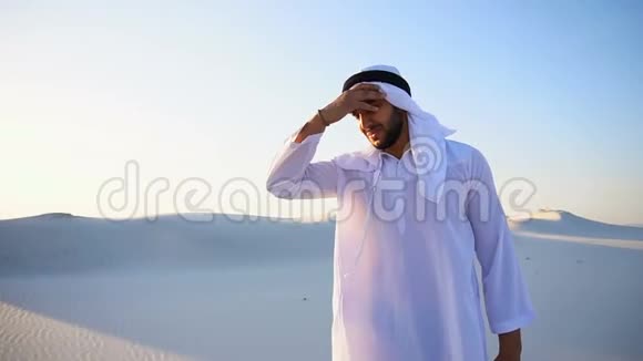 穆斯林男子感到头痛和普遍的不适在温暖的夏天站在沙地沙漠中间视频的预览图