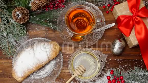 冬茶一杯带蜂蜜和牛角面包的茶雪中圣诞树的树枝顶部视图视频的预览图