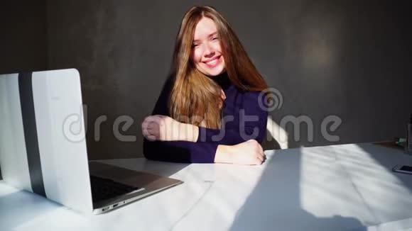 可爱的女人伸出大拇指坐在笔记本电脑附近等待哥哥的在线电话视频的预览图