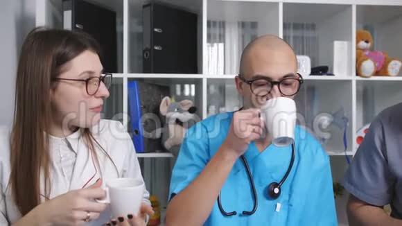 三位医生在休息室里交谈休息时喝咖啡视频的预览图