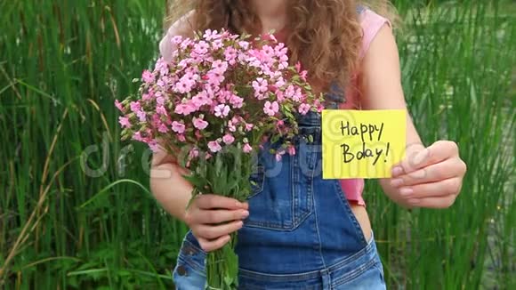 有着生日贺卡和粉色鲜花的漂亮女人视频的预览图
