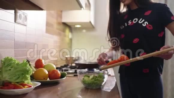 可爱的黑发年轻女人正在家里做饭她做了一些新鲜的沙拉视频的预览图