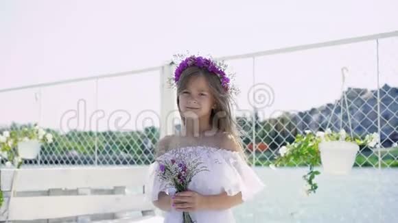 温柔的小女孩手里拿着花微笑着看着海湾酒吧的摄像机视频的预览图