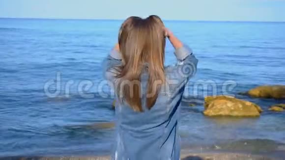 美丽的女孩游客站在海滨发展头发享受自然在晴朗的一天视频的预览图