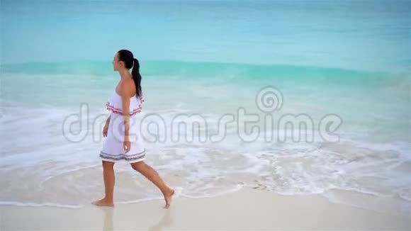 热带海滨的年轻美女上图是白色海滩上穿着漂亮裙子的快乐女孩视频的预览图