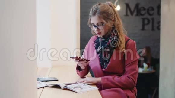 漂亮的年轻女子坐在窗边的咖啡馆为Instagram的帖子拍照放着视频的预览图