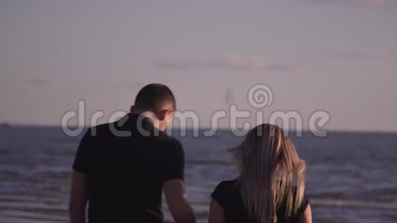 他拥抱和亲吻海滩上的女孩可爱的夫妇在海滩上休息相爱的一对走在视频的预览图