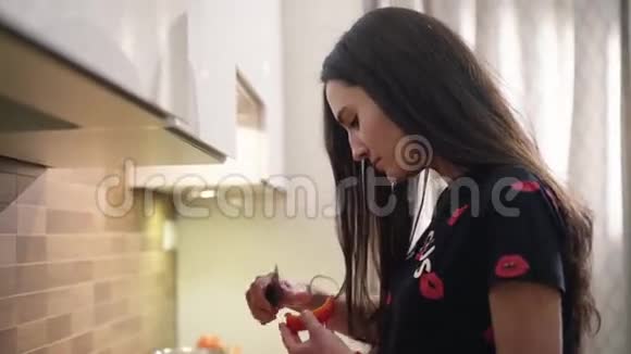 可爱的黑发女孩穿着睡衣在家做早餐蔬菜她正在清洗一些红色的东西视频的预览图