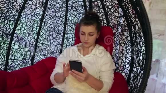 年轻漂亮的女人坐在客厅里在线交流使用手机视频的预览图