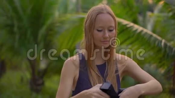 一位美丽的年轻女子的特写镜头在热带公园里使用VR耳机一个戴着虚拟现实眼镜的人感觉他视频的预览图