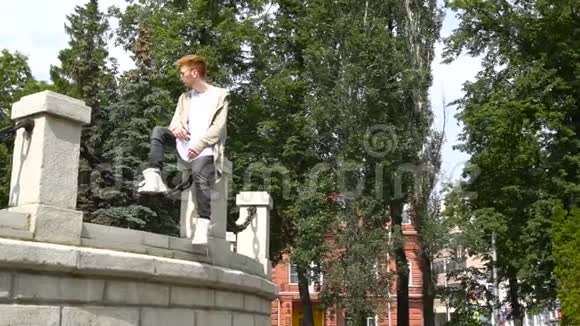 时髦的红头发男人在公园里放松夏季视频的预览图