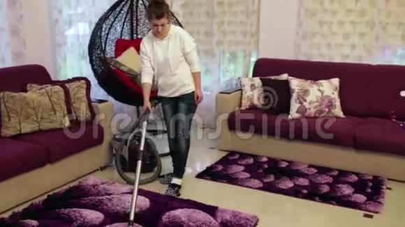 年轻漂亮的女人打扫房子胡佛地毯视频的预览图