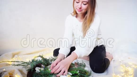 迷人的女人用自己的双手准备圣诞装饰品坐在明亮的房间里闪烁着视频的预览图