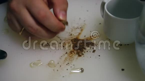 这个人断开了药丸的胶状体把里面的东西洒在桌子上干燥的棕色物质从视频的预览图