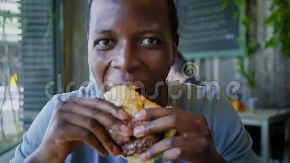 快乐的黑人笑着吃美味的肉汉堡视频的预览图