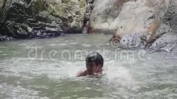 年轻人在热带丛林的瀑布里游泳慢动作1920x1080高清视频的预览图