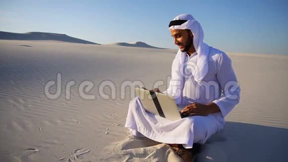 成功的穆斯林阿拉伯阿联酋谢赫建筑师与坐在沙滩上的客户电话沟通笔记本电脑大容量视频的预览图