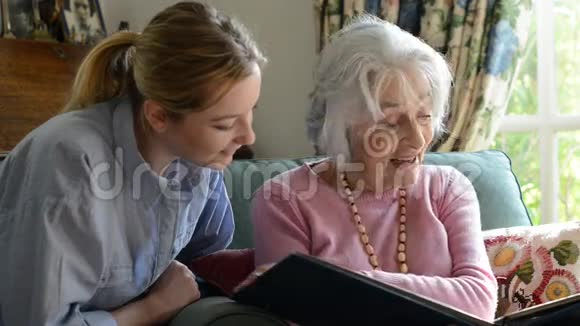 祖母与成年孙女一起看相册视频的预览图