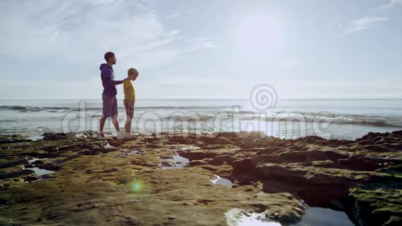 可爱的小男孩和他的父亲站在海岸上视频的预览图