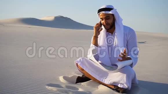 穆斯林设计师阿拉伯谢赫的肖像他在移动与客户建筑坐在沙子与项目视频的预览图