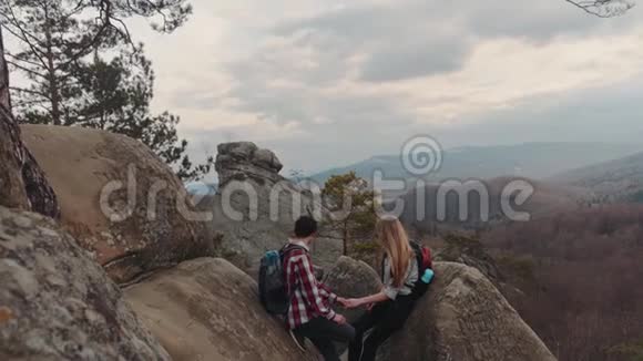 浪漫的徒步旅行者坐在山顶上聊天享受他们在一起的时光一个有着幻想的男孩视频的预览图