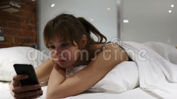卧病在床的女人夜间用智能手机视频的预览图
