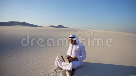 阿联酋酋长国计算机项目专业设计师夏天坐在沙漠的沙滩上视频的预览图