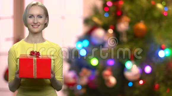 在模糊的圣诞节背景上带礼物盒的女人视频的预览图