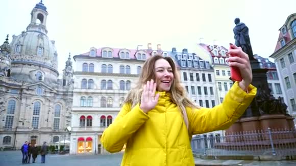 美丽的女孩在Videocall中呼来唤去分享印象站在欧洲城市的中心背景是视频的预览图