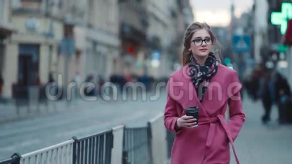 漂亮自信的年轻女性戴着时尚的眼镜穿着五颜六色的粉红色外套拿着一杯咖啡视频的预览图