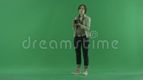 一位年轻女子正在绿色屏幕上调整她的相机视频的预览图