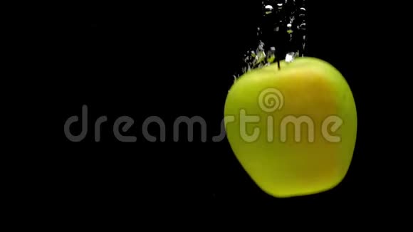 黄色和绿色的苹果在黑色的背景下落入透明的水中视频的预览图