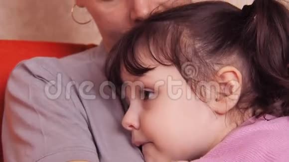 妈妈拥抱女儿一位母亲的女儿抱着坐在橙色沙发上视频的预览图