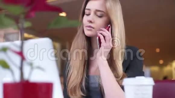 可爱的女孩坐在咖啡馆里她正在用她的智能手机和笔记本工作视频的预览图