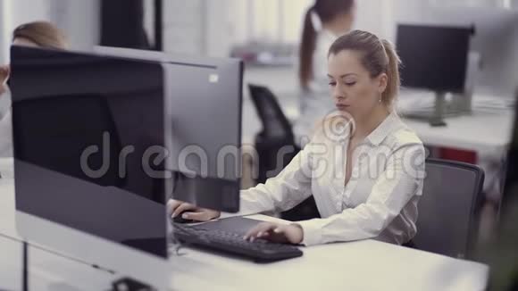 漂亮的高加索女人在办公室里用电脑工作视频的预览图