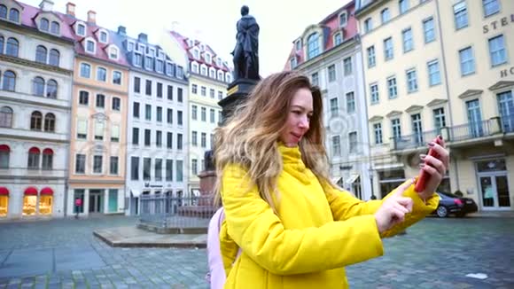 冬季白天漂亮的女聊天者在电视上通过电话和展示欧洲老城德累斯顿的环境视频的预览图