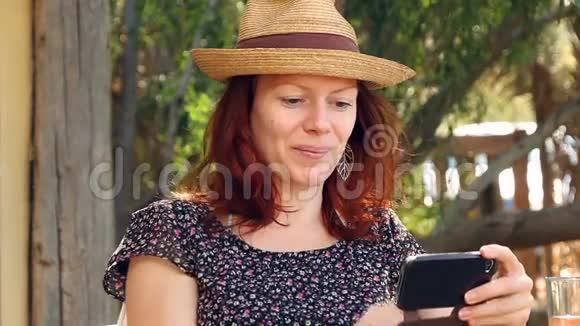 女人坐在花园里在阳光下享受她的智能手机视频的预览图