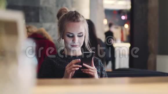 美丽的金发女孩坐在咖啡馆A笑从笑话和模因虚拟现实玩得开心视频的预览图