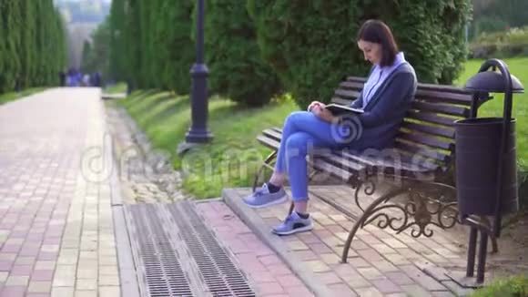 坐在长凳上看书的女孩视频的预览图