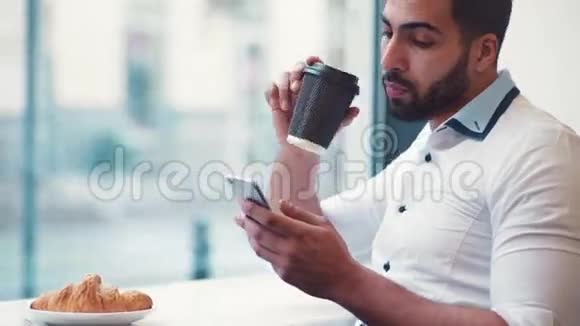 近距离观看一个男人喝咖啡检查他的邮件微笑和短信回到网上在线交流视频的预览图