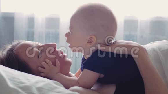 一位年轻快乐的母亲和她的小儿子在床上休息生育观念为人父母母亲美丽视频的预览图