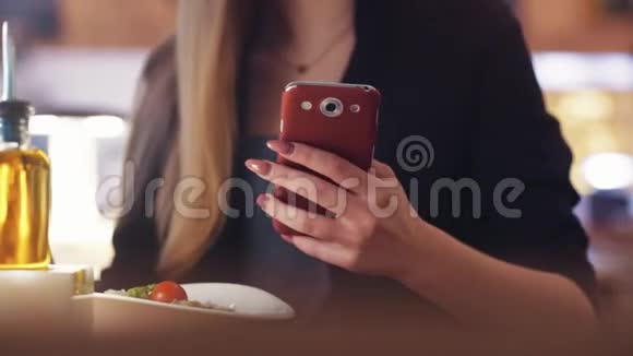 穿黑色夹克的金发女孩坐在咖啡馆A里她正在和一个朋友发短信吃午饭视频的预览图