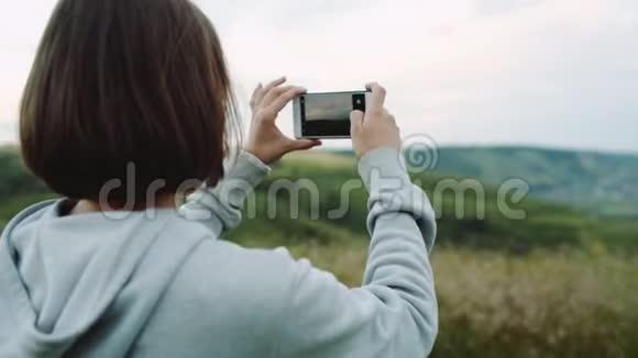 女人在相机手机上拍摄美丽的风景视频的预览图