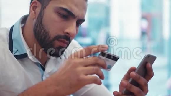 在一家A咖啡馆里奢华的年轻人用他的手机和信用卡进行网上购物现代技术正在上网视频的预览图