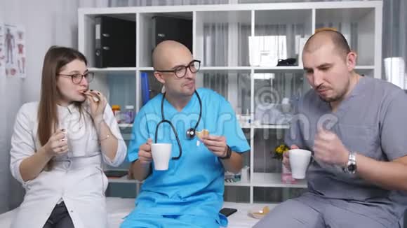 三位医生在休息室里交谈休息时喝咖啡视频的预览图