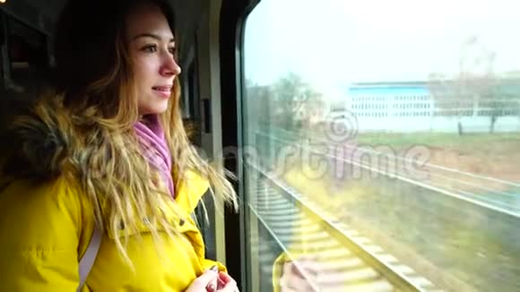 秋天的下午可爱的年轻女子乘火车在铁路运输窗口外看风景视频的预览图