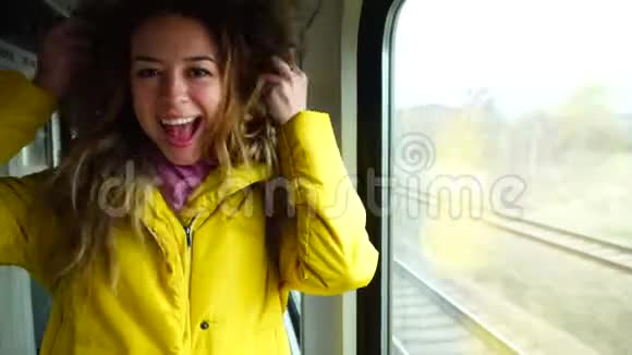 年轻开朗的女人笑和傻瓜在下午靠近窗户的移动火车上用手显示手势视频的预览图