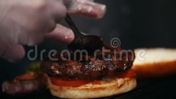 厨师准备汉堡把面包煎在烤架上放西红柿肉和酱汁视频的预览图