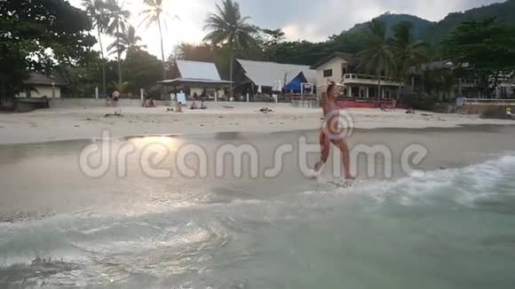 嬉戏的年轻女子跑进大海在热带海滩上旋转享受她的假期慢动作快乐视频的预览图